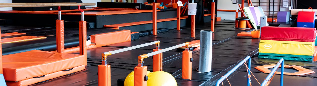 Gymnastics training area with orange and black fitted matting, bars and equipment