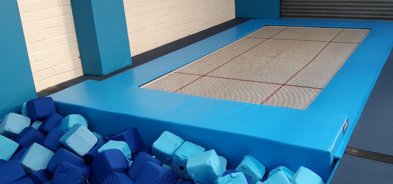 Blue matting around a trampoline and foam pit